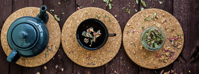 Fototapeta na wymiar a small blue teapot, a mug of tea and dry herbal tea on a wooden background. Herbal medicine. tea from flowers.