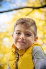 Cute kid against a yellow tree in autumn