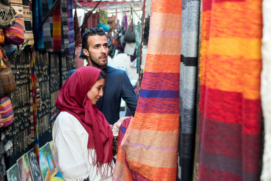 Smiling young muslim couple shopping carpets in a textile store