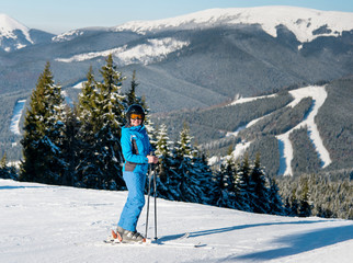 Full length shot of a happy woman skier skiing on the slope at winter ski resort in sunny beautiful...