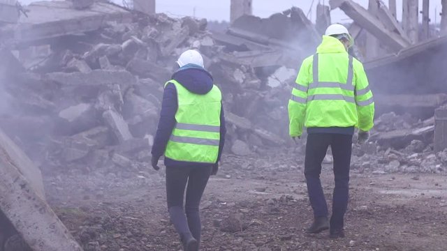 two employees of service of rescue the signal in the green vests on the ruins after the earthquake