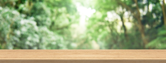 Wood table top and blur green forest for product and display montage banner size