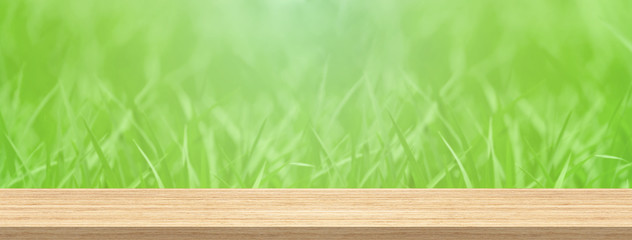 Wood table top and blur green grass for product and display montage banner size