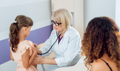 Friendly doctor pediatrician with patient child at clinic