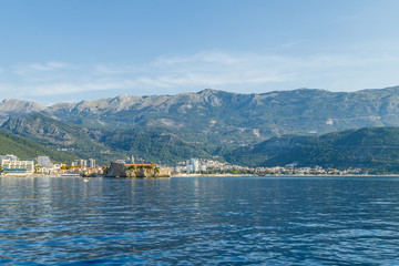 Fototapeta premium View of the mountains and the resort town of Budva and its fortress in Montenegro from the sea