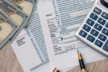 Tax form with dollar, calculator and pen