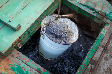 The full bucket of clear water rises from the deep well