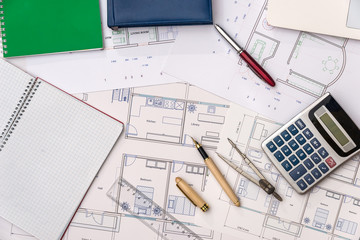 Top view of house plan with laptop, calculator and pencils