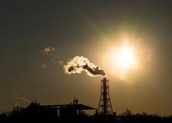 Factory chimney emits or discharges heavy smokes during sunset creating pollution. 