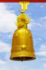 Obraz premium Golden bell hang with red iron beams large size with bright sky and cloud as the background.