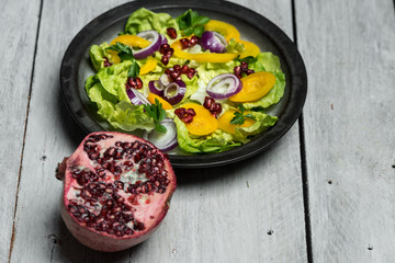 Healthy breakfast, fresh salad with the addition of purple onion and pomegranate seeds on white, wooden background