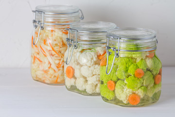 Fermented preserved vegetarian food concept. Cabbage, broccoli, caulie, sauerkraut sour glass jars on white background