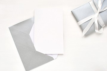Christmas, New Years, wedding greeting card, invitation mock up, blank card and silver envelope, flat lay on white background.