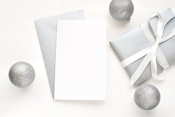 Christmas, New Years greeting card mock up, blank card, silver envelope, gift with white ribbon and Christmas decorations.