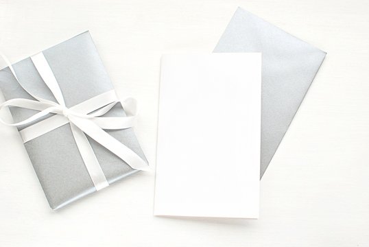 Greeting card mock up template to place your design. Blank white card, silver envelope, gift box, top view.