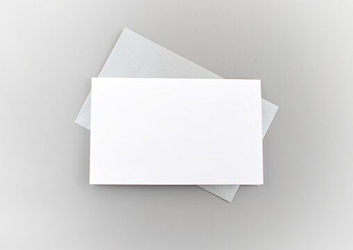 White greeting card and silver envelope on gray background to place your design. 