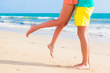 legs of young hugging couple in love on tropical turquoise beach