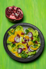 healthy diet, fresh salad with the addition of purple onion and pomegranate seeds on green background