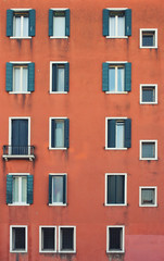 Many windows. Medieval facade. Window shutters. Architectural style of Italy. Facade with many doors and windows
