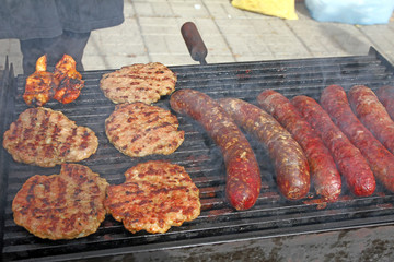 Grilling sausages, burgers, pork steak on barbecues gas grill for party. Hot dogs,sausages and hamburgers on a barbeque, bbq. Smokes meat food outdoors, fast food. Hamburgers. Pleskavitsa