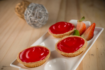 Strawberry jam tart, homemade bakery on white dish and wooden background, selective focus