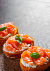 Canapes with smoked salmon and cream cheese on wooden table background