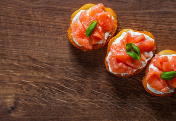 Canapes with smoked salmon and cream cheese on wooden table background