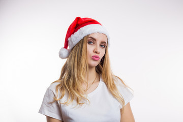 Christmas Santa woman in a red hat shows the kiss on a white background