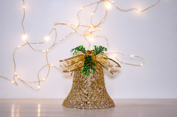 Christmas decoration in the form of a golden bell on a white background. Lights of garland on a white background.