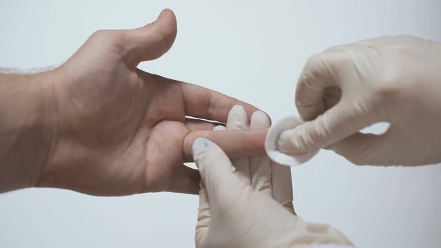 the doctor processes the patient&rsquo;s finger with a disinfectant before taking the blood for analysis
