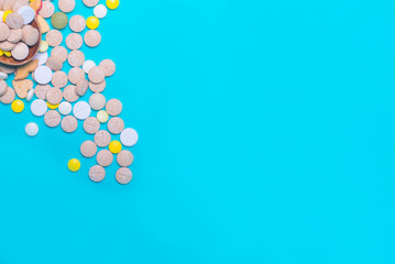 Top view of pharmaceutical medicine pills, capsules and tablets w/ wooden spoon on light blue background. Vitamin and supplement. Health behavior concept. Minimal style. Creative idea.