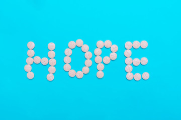 Assorted pharmaceutical medicine pills, tablets and capsules on blue background. word hope. Help word concept