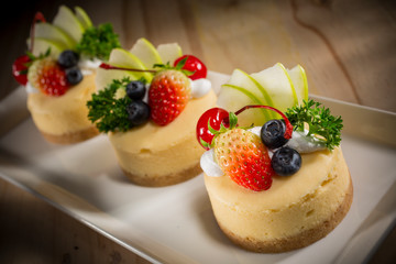 Cheesecake With Fruit Topping, Mixed fruit Cheesecake, Homemade cake on white dish, selective focus