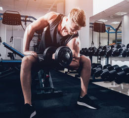 Handsome muscular man working out with dumbbells.