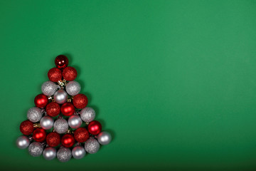 Baubles forming Christmas tree on green background