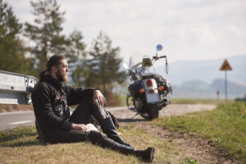 Tall athletic sportive muscular biker in black leather clothing sitting at cruiser powerful...