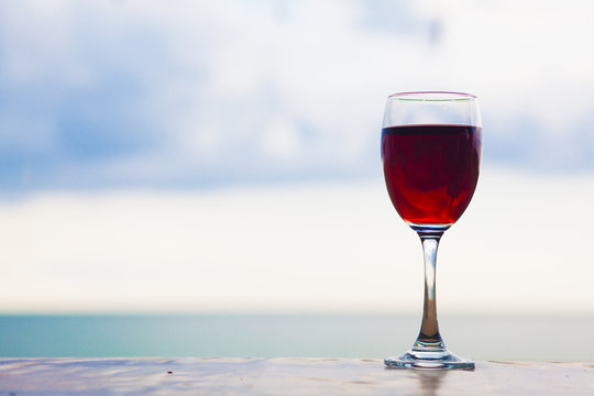 glass of red wine in the table by the beach