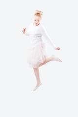 Fototapeta premium Young caucasian women in white shirt and tutu skirt jumping high with joy on isolated white background. Light, dreamy and airy look.