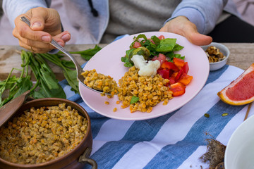 Woman hand put, add lentil to buddha bowl plate with red pepper bell salad, cooked vegetables (broccoli, brussels sprouts, cauliflower), spinach, grapefruit, lentil. Vegan vegetarian healthy food