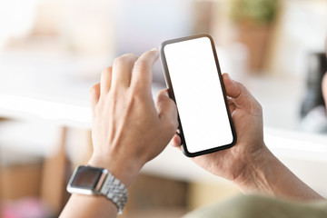 Male hand holding blank screen mobile phone in office.