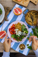 Hand put, add vegetables to buddha bowl plate with red pepper bell salad, cooked vegetables (broccoli, brussels sprouts, cauliflower), spinach, grapefruit, Indian lentil. Vegan vegetarian healthy food