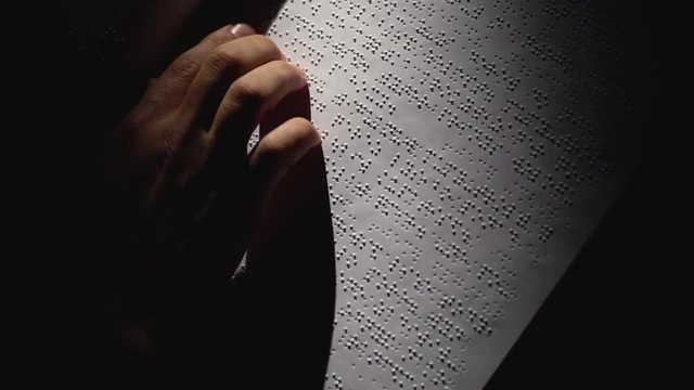 Male Hands Reading a Braille Book in dark room . Close up