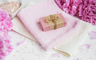 Obraz na płótnie Canvas bars of handmade soap, soft towels and peony flowers