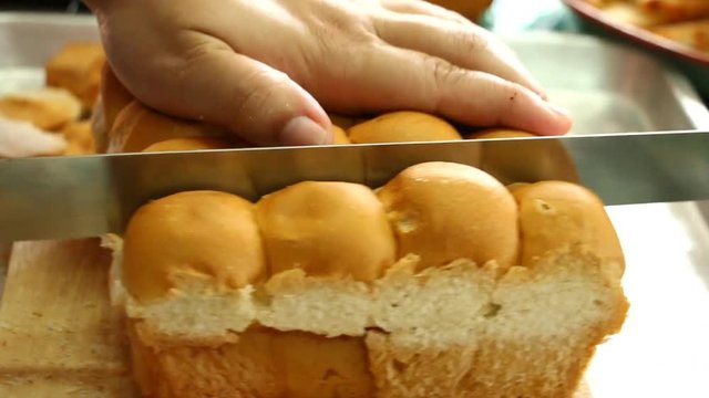 Chef  cutting bread by bread knife 
