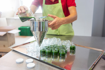 Frau füllt gesunden Weizengras Smoothie in Gläschen ab