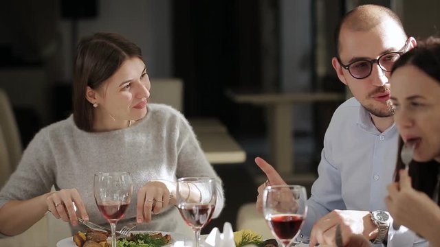 Group of friends having lunch in restaurant. A man and two women having lunch at restaurant and drinking wine.