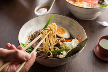 Man eating Asian ramen with tuna and noodles in a restaurant