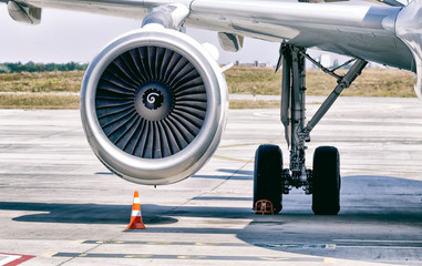 Engine of modern passenger jet airplane. Rotating fan and turbine blades. Traffic cone near it. Close-up front view.