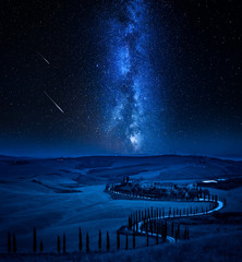 Milky way and winding road with cypressesin Italy