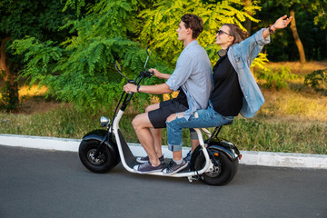 Lovely young couple driving electric bike during summer Modern city life and transportation